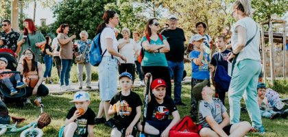 A diverse group of families and children enjoying an outdoor event on a sunny day in a park setting.