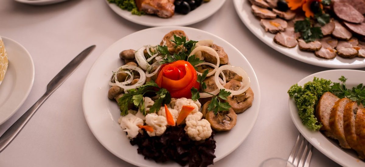 Beautifully arranged gourmet plates with meats, cheeses, and garnishes on a white table setting.
