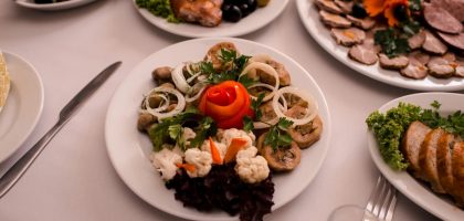 Beautifully arranged gourmet plates with meats, cheeses, and garnishes on a white table setting.