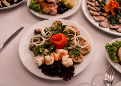 Beautifully arranged gourmet plates with meats, cheeses, and garnishes on a white table setting.