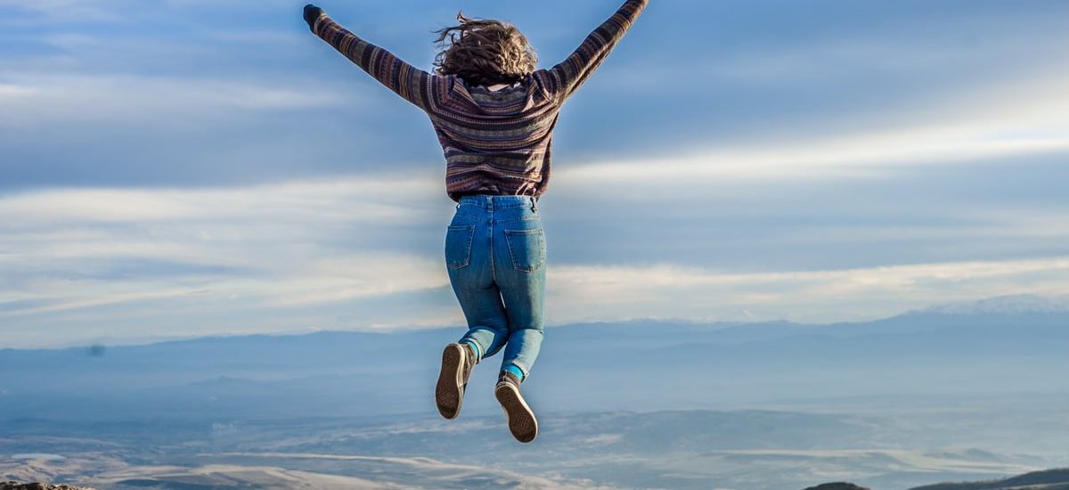 Person jumping on a mountain peak, celebrating adventure and freedom.