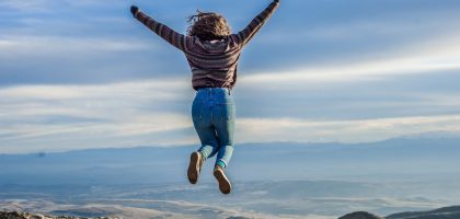 Person jumping on a mountain peak, celebrating adventure and freedom.
