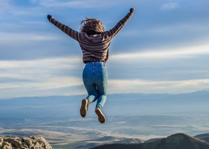 Person jumping on a mountain peak, celebrating adventure and freedom.